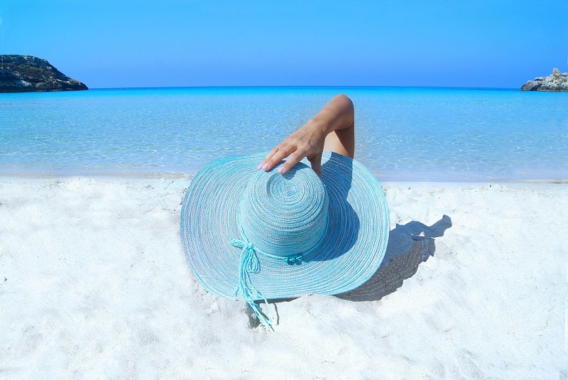 Kobieta w kapeluszu wypoczywająca na plaży