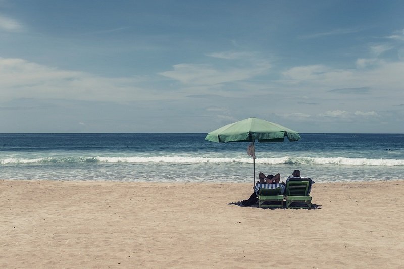 Dwoje ludzi odpoczywających pod parasolem na plaży